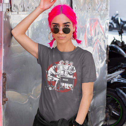 A pink haired woman in sunglasses, leaning against a wall, wearing an anthracite short sleeved crew neck t-shirt with a white and red graphic of three clowns laughing and pointing at an office worker.