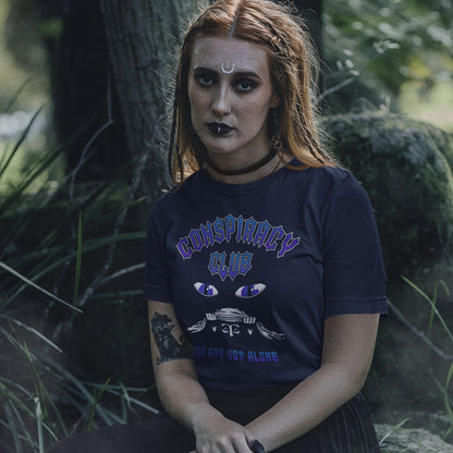 Person wearing a 'Conspiracy Club' t-shirt in a forest setting. A conspiracy theorist t shirt design for all conspiracy lovers who think big brother is watching. join the club, expand your independent thinking, question everything. Think outside the box. Made from 100% organic ring-spun cotton, this funny conspiracy theory t shirt is unisex, high-quality, super comfy, and best of all, eco-friendly.