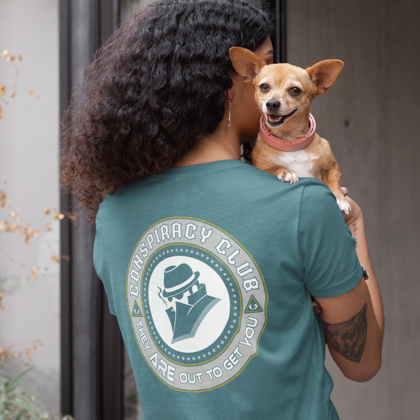 Person wearing a stargazer t-shirt with ' Conspiracy Club' design, holding a small dog. A conspiracy theorist t shirt. These days there's a conspiracy theory for every occasion, join the club, expand your alternative imagination. Think outside the box. Underground art on apparel. Made from 100% organic ring-spun cotton, these conspiracy theory t shirts are unisex, high-quality, super comfy, and best of all, eco-friendly.