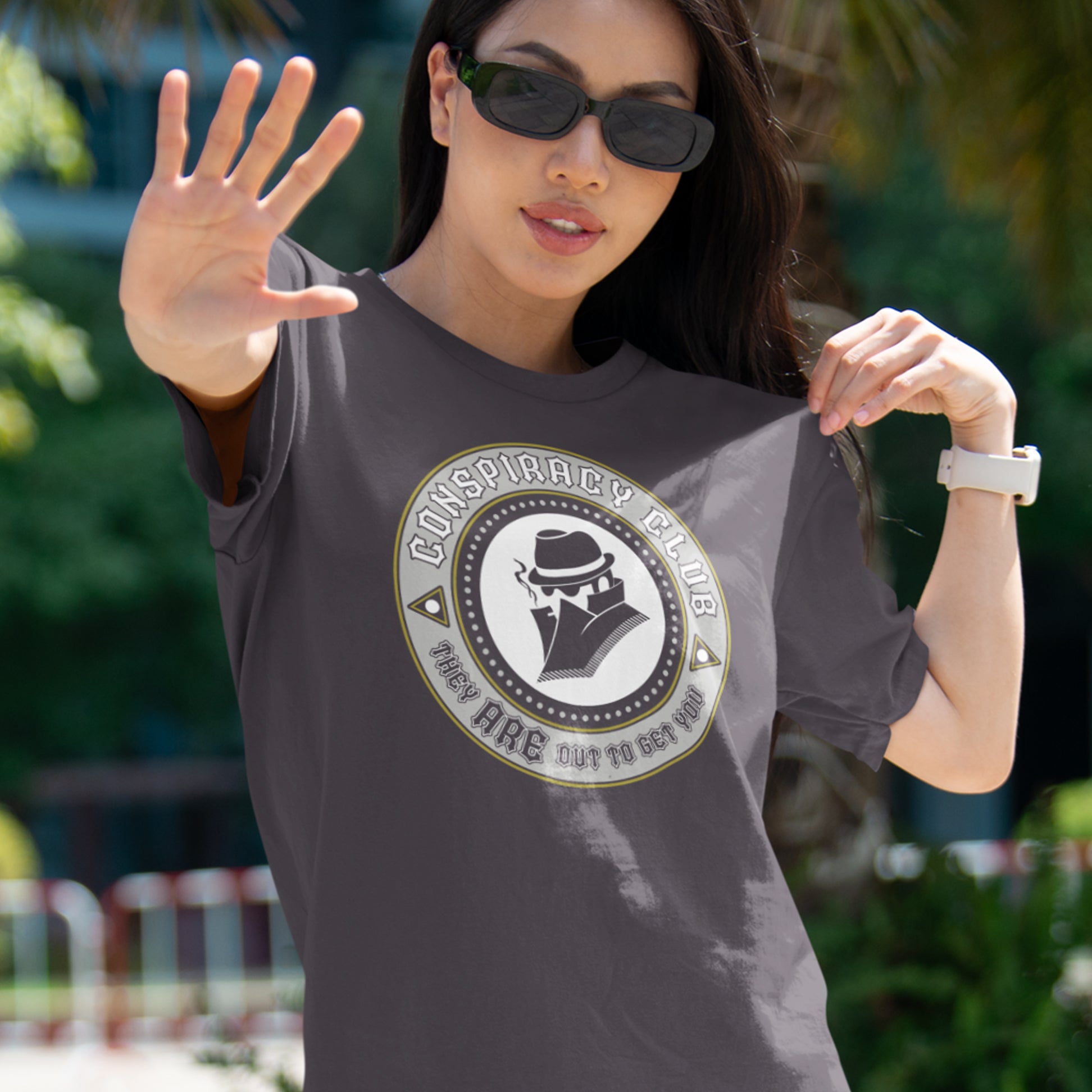 Woman wearing a t-shirt with a conspiracy theory graphic design outdoors. These days there's a conspiracy theory for every occasion, join the club, expand your alternative imagination. Think outside the box. Underground art on apparel. Made from 100% organic ring-spun cotton, this conspiracy theory t-shirt is unisex, high-quality, super comfy, and best of all, eco-friendly.