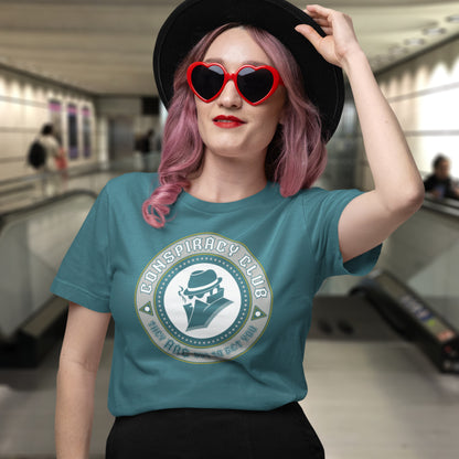 Person wearing a teal t-shirt with 'Conspiracy Club' design in an indoor setting. These days there's a conspiracy theory for every occasion, join the club, expand your alternative imagination. Think outside the box. Underground art on apparel. Made from 100% organic ring-spun cotton, this conspiracy theory t-shirt is unisex, high-quality, super comfy, and best of all, eco-friendly.