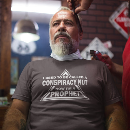 Man getting a haircut with a shirt that reads 'I used to be called a conspiracy nut now I'm a prophet' in a barbershop setting. This conspiracy theorist t-shirt design is for anyone who used to get funny looks for their alternative view, but now gets greeted with nods of understanding as your earlier rantings come true. Made from 100% organic ring-spun cotton, this conspiracy theorist t-shirt is unisex, high-quality, super comfy, and best of all, eco-friendly.