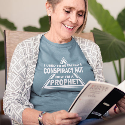 Woman wearing a shirt with text reading 'I used to be called a conspiracy nut now I'm a prophet' while reading a book. This conspiracy theorist t-shirt design is for anyone who used to get funny looks for their alternative view, but now gets greeted with nods of understanding as your earlier rantings come true. Made from 100% organic ring-spun cotton, this conspiracy theorist t-shirt is unisex, high-quality, super comfy, and best of all, eco-friendly.