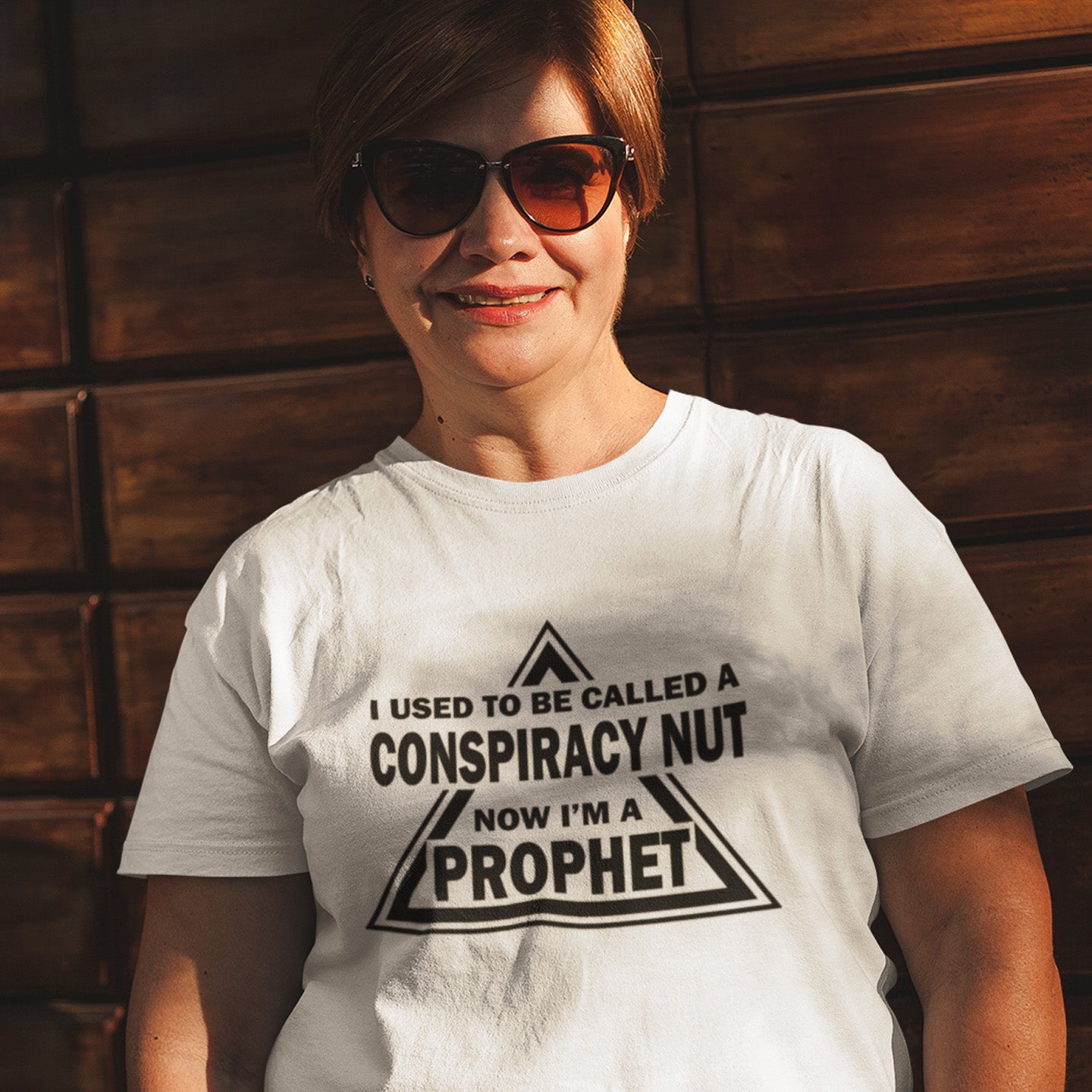 Person wearing a white t-shirt with a printed message against a wooden wall. This conspiracy theorist t-shirt design is for anyone who used to get funny looks for their alternative view, but now gets greeted with nods of understanding as your earlier rantings come true. Made from 100% organic ring-spun cotton, this conspiracy theorist t-shirt is unisex, high-quality, super comfy, and best of all, eco-friendly.