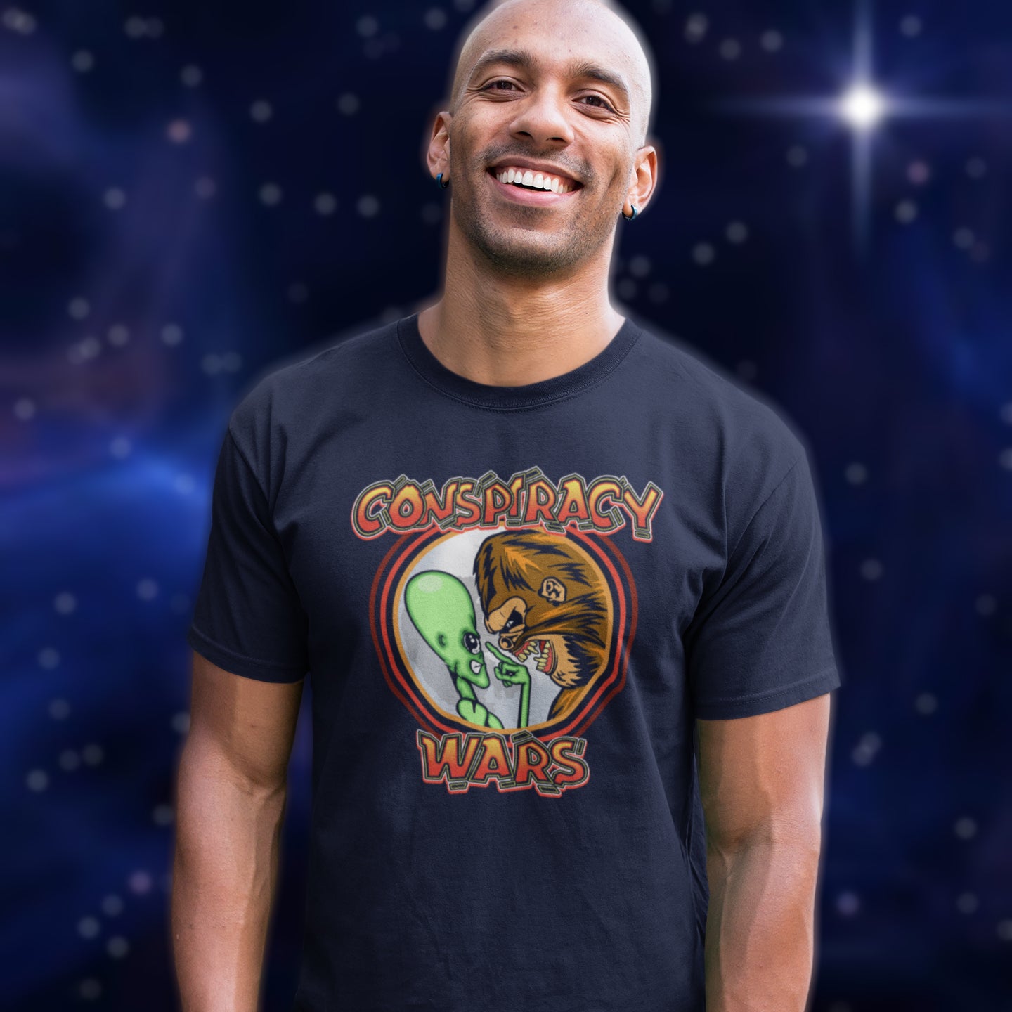 Man wearing a French navy t-shirt with 'Conspiracy Wars' graphic design against a starry space background. This funny conspiracy t-shirt suggests competition between the two main rivals for cover up stories. Aliens Vs Bigfoot, Kings of conspiracy face off. Made from 100% organic ring-spun cotton, this witty conspiracy theory t-shirt is unisex, high-quality, super comfy, and best of all, eco-friendly.
