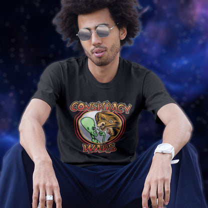 Person wearing a black t-shirt with a graphic design sitting against a dark background. This funny conspiracy theory t shirt suggests competition between the two main rivals for cover up stories. Aliens Vs Bigfoot, Kings of conspiracy face off. Made from 100% organic ring-spun cotton, this witty conspiracy theorist t shirt is unisex, high-quality, super comfy, and best of all, eco-friendly.