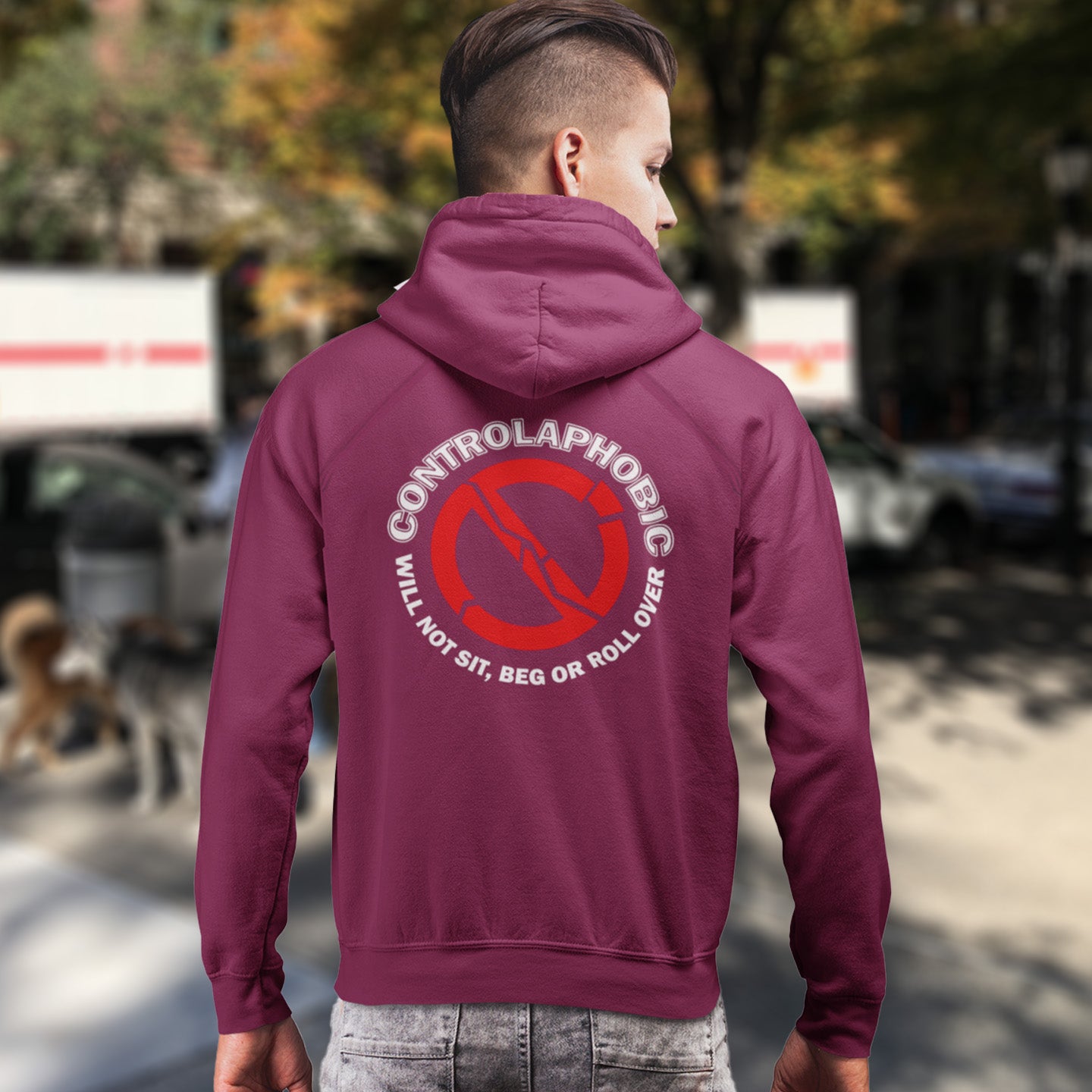 Person wearing a burgundy hoodie with a humorous graphic and text on the back, standing outdoors. A satirical anti-establishment hoodie suggesting there is a lack of freedom of choice, and too much control, in modern society. If you find yourself unable to follow commands and you're not a dog, You may have controlaphobia. Comfortable and practical. It's extra soft and has a convenient front pouch pocket. Made from organic cotton and recycled polyester, this social awareness hoodie is a great eco-friendly ch