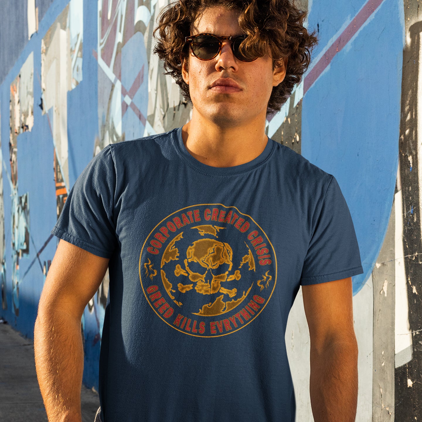 Man wearing a French navy blue t-shirt with a gold graphic design in an urban setting. AN anti-corporate climate concern t-shirt encouraging social awareness and support to save our planet from corporate negligence. Make it clear you are no fool to where the climate problem blame should be placed with this original design. Made from 100% organic ring-spun cotton, this anti corporate t-shirt is unisex, high-quality, super comfy, and best of all, eco-friendly.