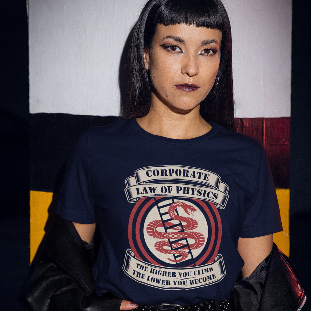 Person wearing a navy blue t-shirt with a graphic design and text. A satirical anti corporate t shirt depicting big business as heartless and lacking in morality. In the ever increasing cut throat environment of corporate business it appears that the less integrity you have the more successful you will be. Made from 100% organic ring-spun cotton, this broken society t shirt is unisex, high quality, super comfy, and best of all, eco-friendly.