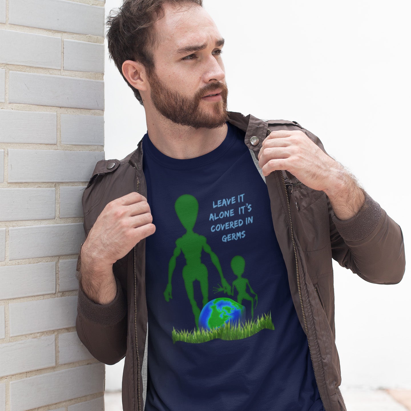 Man wearing a French navy blue t-shirt with an alien and Earth graphic and text. A funny alien t-shirt design with a subtle overpopulation message. In the grand scheme of things, our planet and universe could just be the school project of a child from a superior race. Made from 100% organic ring-spun cotton, this witty alien t-shirt is unisex, high-quality, super comfy, and best of all, eco-friendly.
