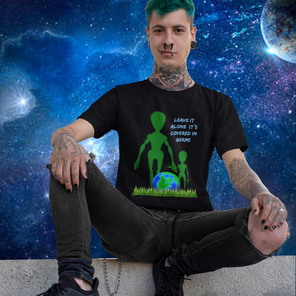 Person wearing a black t-shirt with an alien design and text, sitting against a space-themed background. A funny alien t-shirt design with a subtle overpopulation message. In the grand scheme of things, our planet and universe could just be the school project of a child from a superior race. Made from 100% organic ring-spun cotton, this witty alien t-shirt is unisex, high-quality, super comfy, and best of all, eco-friendly.