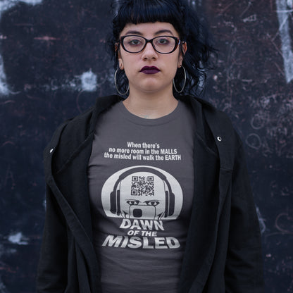 Person wearing a t-shirt with a graphic design and text, standing against a dark textured wall. A counterculture t-shirt in the theme of a famous 1970's horror movie. This satirical design highlights the modern consumer who buys what they are told to buy by social media and corporate advertising. Made from 100% organic ring-spun cotton, this underground anti-consumerism t-shirt is unisex, high-quality, super comfy, and best of all, eco-friendly.