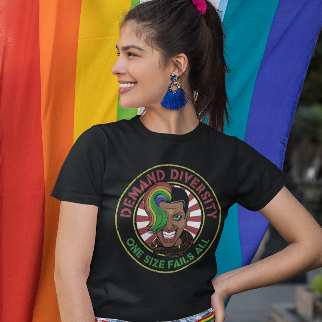 Woman standing in front of a rainbow flag, wearing a black t shirt with a  Demand diversity logo.