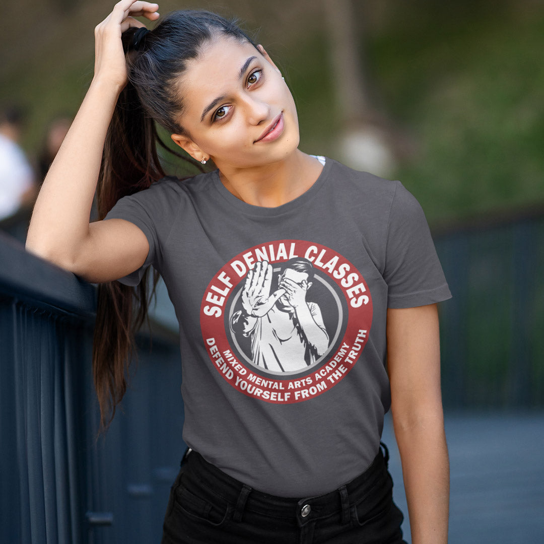 Woman wearing a grey t-shirt with a graphic design and text. This emotional intelligence t shirt satirically highlights self denial as an increasing part of everyday life and suggests we could provide classes to improve it. This sarcastic urban art design laughs at people who want to protect themselves from the truth. Made from 100% organic ring-spun cotton, this broken society t shirt is unisex, high-quality, super comfy, and best of all, eco-friendly.