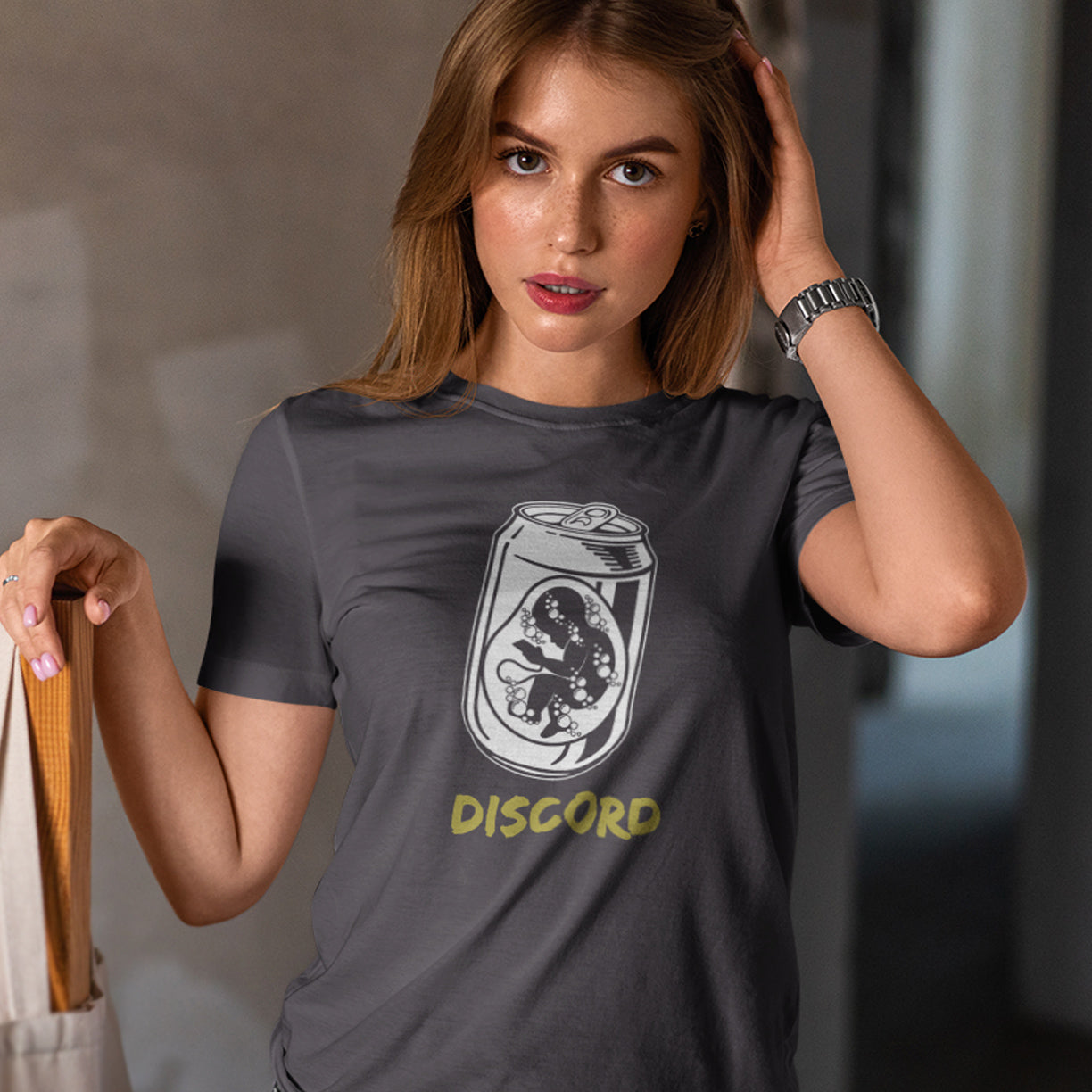 Woman wearing an anthracite t-shirt with a graphic design and 'DISCORD' text. A Banksy style t-shirt suggesting a discord between modern generations and nature. A stencil art testament to the soda pop generation. Brought up on energy drinks and born with a Wi-Fi connection. Made from 100% organic ring-spun cotton, this street art t-shirt is unisex, high-quality, super comfy, and best of all, eco-friendly.
