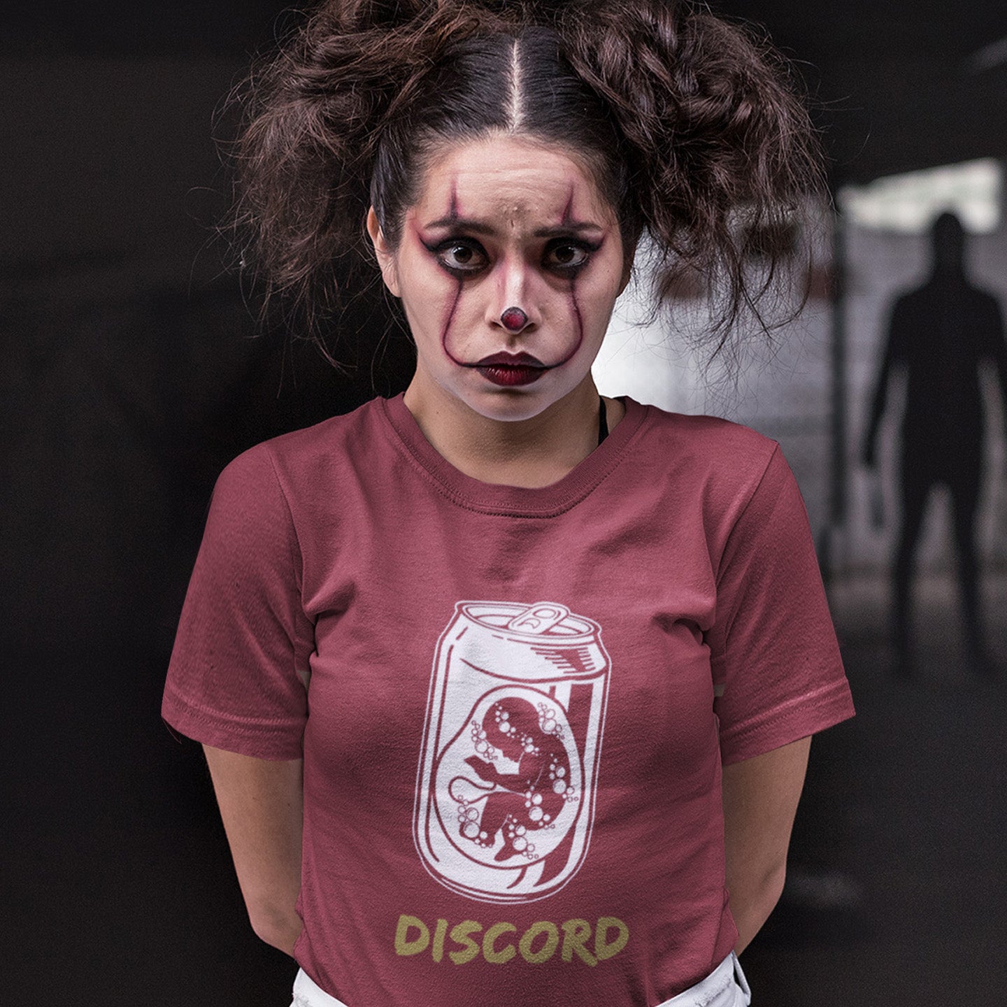 Person wearing a burgundy t-shirt with Discord logo and text, against a dark background. A Banksy style t-shirt suggesting a discord between modern generations and nature. A stencil art testament to the soda pop generation. Brought up on energy drinks and born with a Wi-Fi connection. Made from 100% organic ring-spun cotton, this street art t-shirt is unisex, high-quality, super comfy, and best of all, eco-friendly.