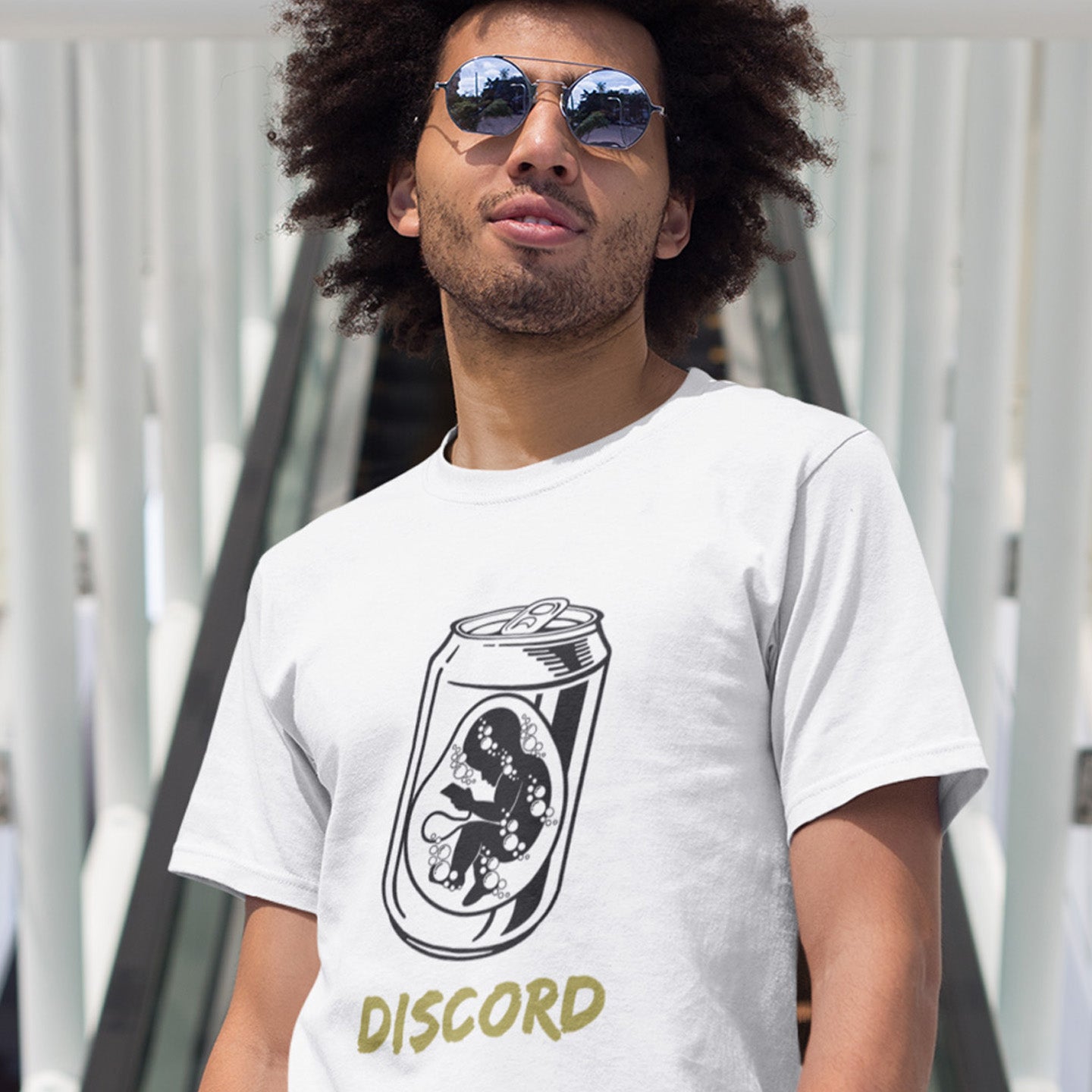 Man wearing a white t-shirt with a graphic design and 'DISCORD' text. A Banksy style t-shirt suggesting a discord between modern generations and nature. A stencil art testament to the soda pop generation. Brought up on energy drinks and born with a Wi-Fi connection. Made from 100% organic ring-spun cotton, this street art t-shirt is unisex, high-quality, super comfy, and best of all, eco-friendly.