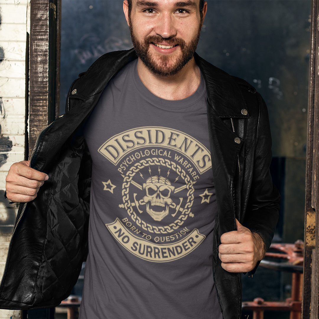 Man wearing an anthracite t-shirt with 'Dissidents' design, standing indoors. An anti government t shirt suggesting we are living in a psychological war. Designed in a motorcycle club style, this dissident t shirt is for those among us that feel they are fighting for their freedom to think independently and to make their own choices. Made from 100% organic ring-spun cotton, this non conformist t shirt is unisex, high-quality, super comfy, and best of all, eco-friendly.