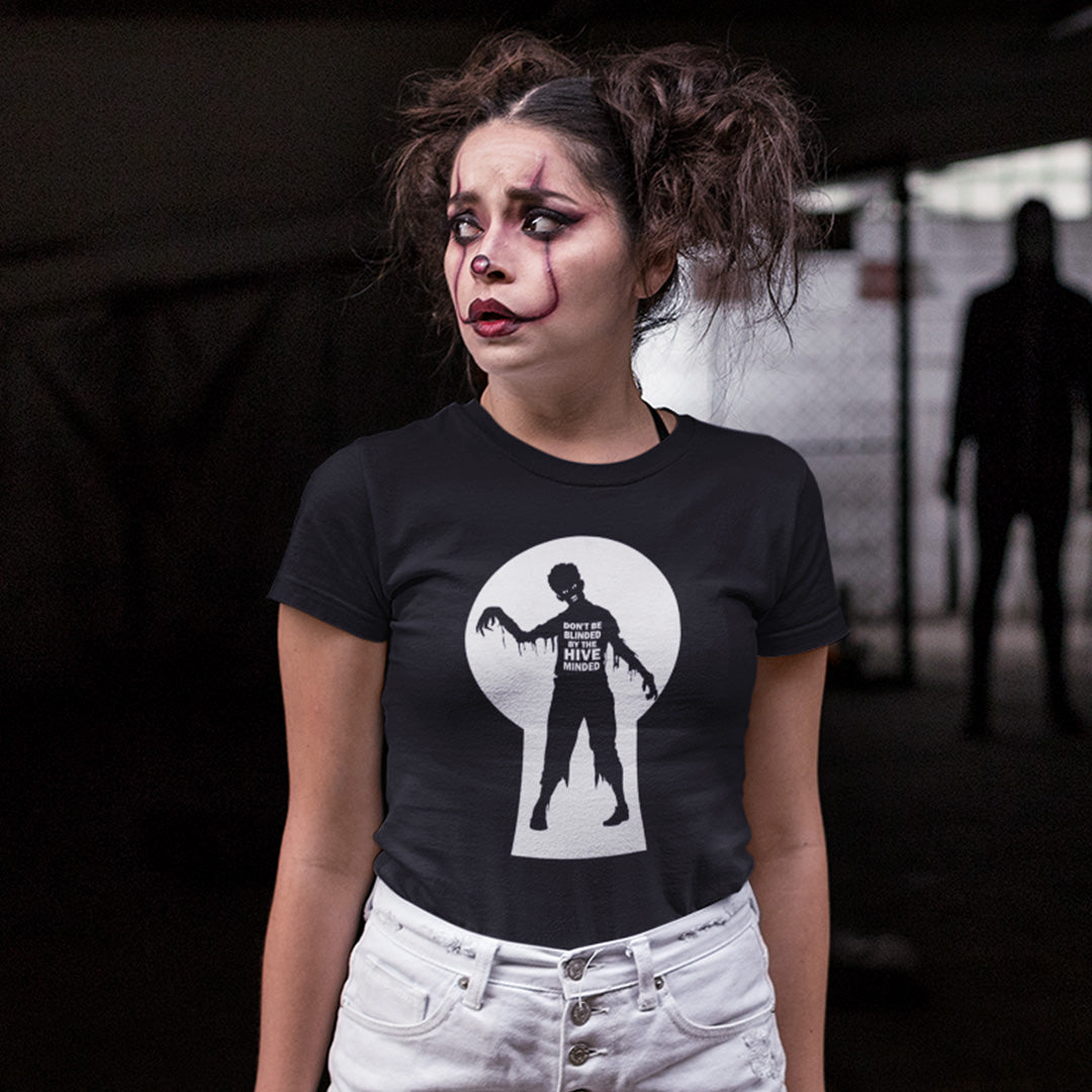 A woman with dramatic zombie makeup and messy hair wears a black graphic t-shirt featuring a white keyhole design with a zombie silhouette.