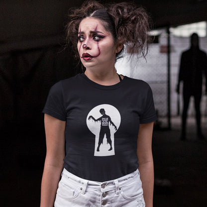 A woman with clown makeup, looking worried with a man standing in the shadows, wearing a black  t-shirt with a zombie through a key hole design with "DON'T BE BLINDED BY THE HIVE MINDED" text.