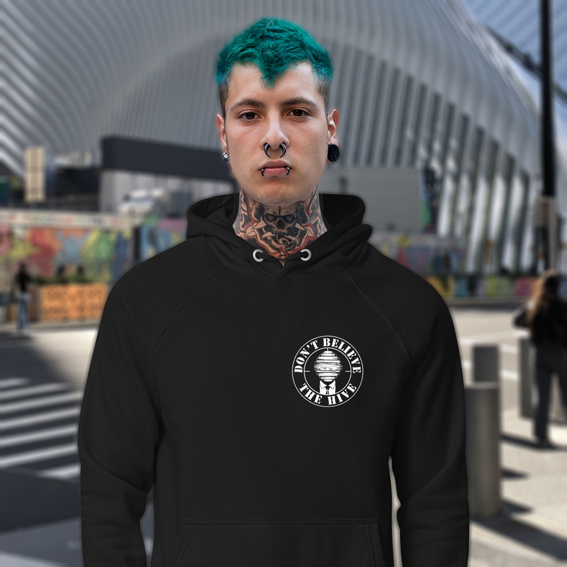 Person wearing a black hoodie with a logo and text, standing in an urban setting. A anti establishment hoodie. In an ever increasing world of media influence and misinformation, can 'The Majority' be trusted any more ? Don't get blinded by the hive minded. Support independent thought with this unique hoodie. Comfortable and practical. It's extra soft and has a convenient front pouch pocket. Made from organic cotton and recycled polyester, this social awareness hoodie is a great eco-friendly choice.