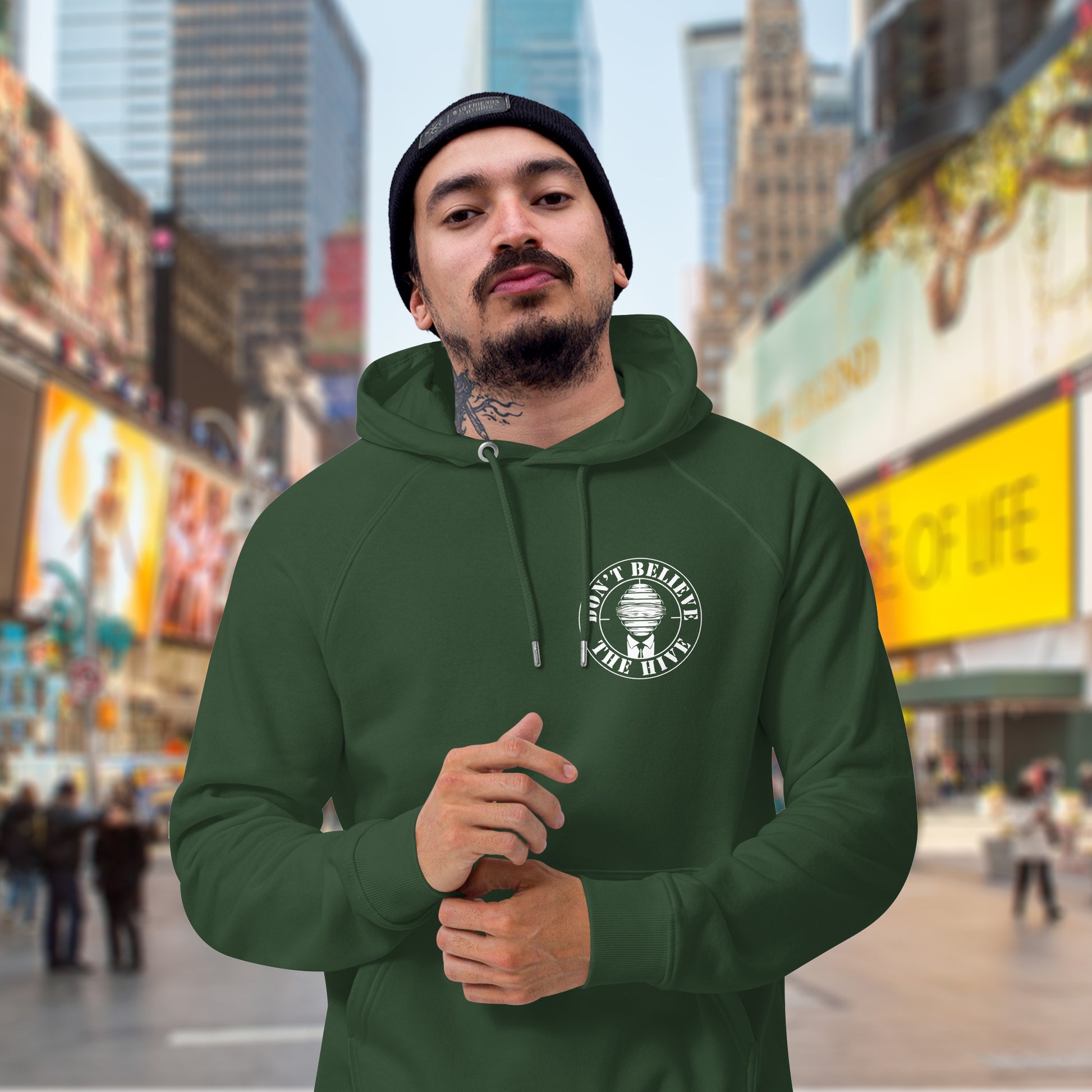 Man wearing a bottle green hoodie with a logo in Times Square, New York City. A anti establishment hoodie. In an ever increasing world of media influence and misinformation, can 'The Majority' be trusted any more ? Don't get blinded by the hive minded. Support independent thought with this unique hoodie. Comfortable and practical. It's extra soft and has a convenient front pouch pocket. Made from organic cotton and recycled polyester, this social awareness hoodie is a great eco-friendly choice.