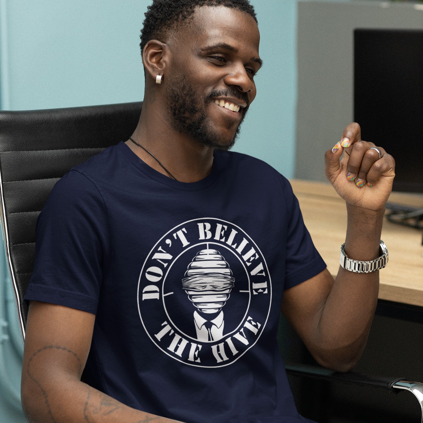 Man wearing a French navy blue t-shirt with a graphic design and text, sitting in an office chair. A street art t shirt design for an ever increasing world of media influence and misinformation. Can 'The Majority' be trusted any more ? Don't get blinded by the hive minded. Support independent thought with this unique urban art t shirt. Made from 100% organic ring-spun cotton, this social awareness t shirt is unisex, high-quality, super comfy, and best of all, eco-friendly.