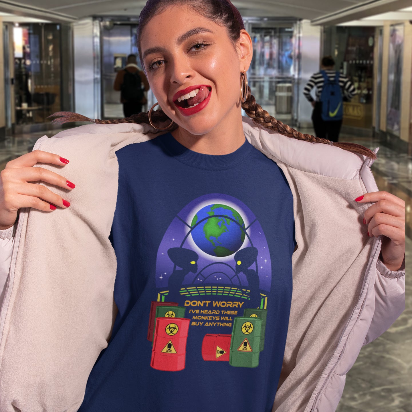 Woman wearing a French navy graphic t-shirt in an indoor setting. A funny alien t shirt design showing a humorous view of how aliens must see us. It's universally acknowledged that humans have an obsession with shopping and buying things they don't need. Made from 100% organic ring-spun cotton, these cool sci fi t shirts are unisex, high-quality, super comfy, and best of all, eco-friendly.