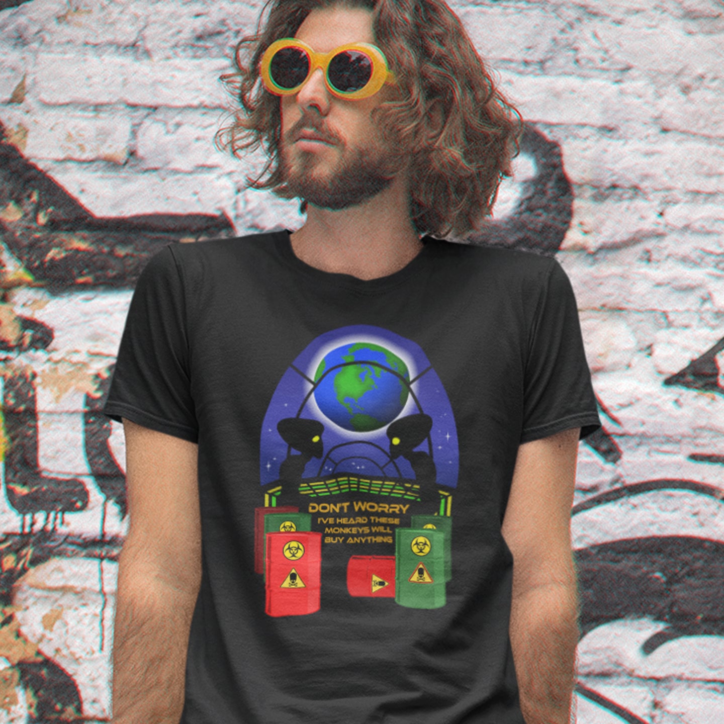 Person wearing a black t-shirt with a colorful graphic design in front of a graffiti-covered wall. A funny alien t shirt design showing a humorous view of how aliens must see us. It's universally acknowledged that humans have an obsession with shopping and buying things they don't need. Made from 100% organic ring-spun cotton, these cool sci fi t shirts are unisex, high-quality, super comfy, and best of all, eco-friendly.