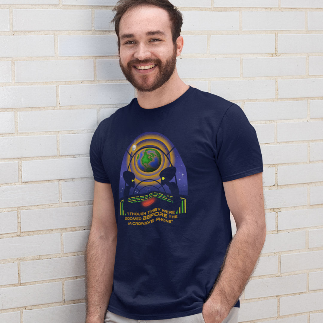 Man standing against a white brick wall wearing a funny alien t shirt. A funny alien t shirt satirically exposing the dangers of microwaves. We probably seem quite masochistic from an outsiders point of view and the aliens must wonder what we are doing in the name of progression. A global warming t shirt design for alien fans. Made from 100% organic ring-spun cotton, this cool sci fi t shirt is unisex, high-quality, super comfy, and best of all, eco-friendly.