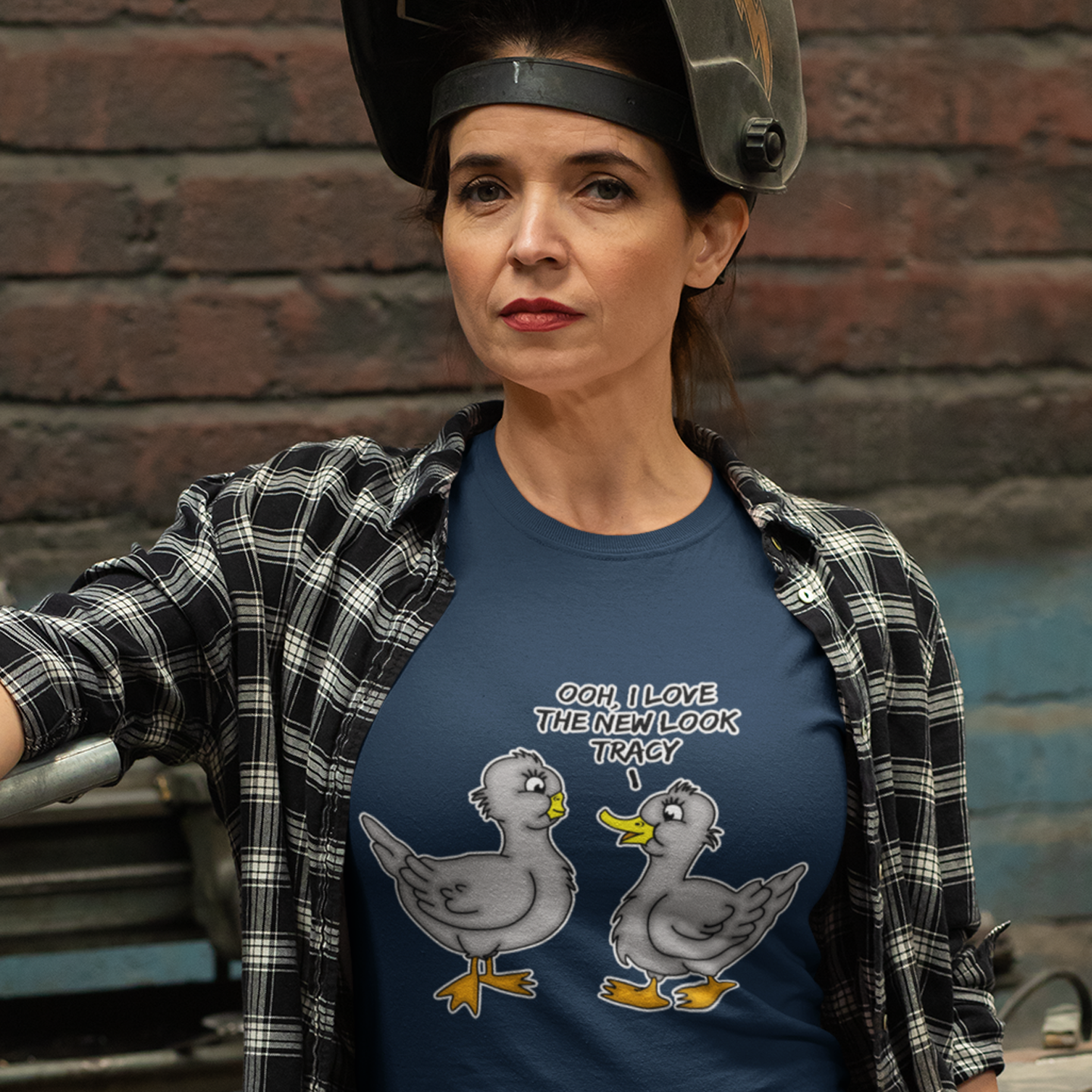 Person wearing a French navy blue t-shirt with cartoon ducks and text, standing against a brick wall. A social issues t shirt design mocking the idea of lip fillers. In a alternative reality are ducks having surgery to make their lips look like humans ? Counterculture cartoon. Made from 100% organic ring-spun cotton, this social awareness t shirt is unisex, high-quality, super comfy, and best of all, eco-friendly.