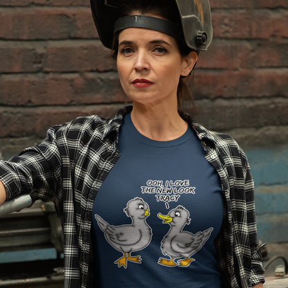 Person wearing a French navy blue t-shirt with cartoon ducks and text, standing against a brick wall. A social issues t shirt design mocking the idea of lip fillers. In a alternative reality are ducks having surgery to make their lips look like humans ? Counterculture cartoon. Made from 100% organic ring-spun cotton, this social awareness t shirt is unisex, high-quality, super comfy, and best of all, eco-friendly.