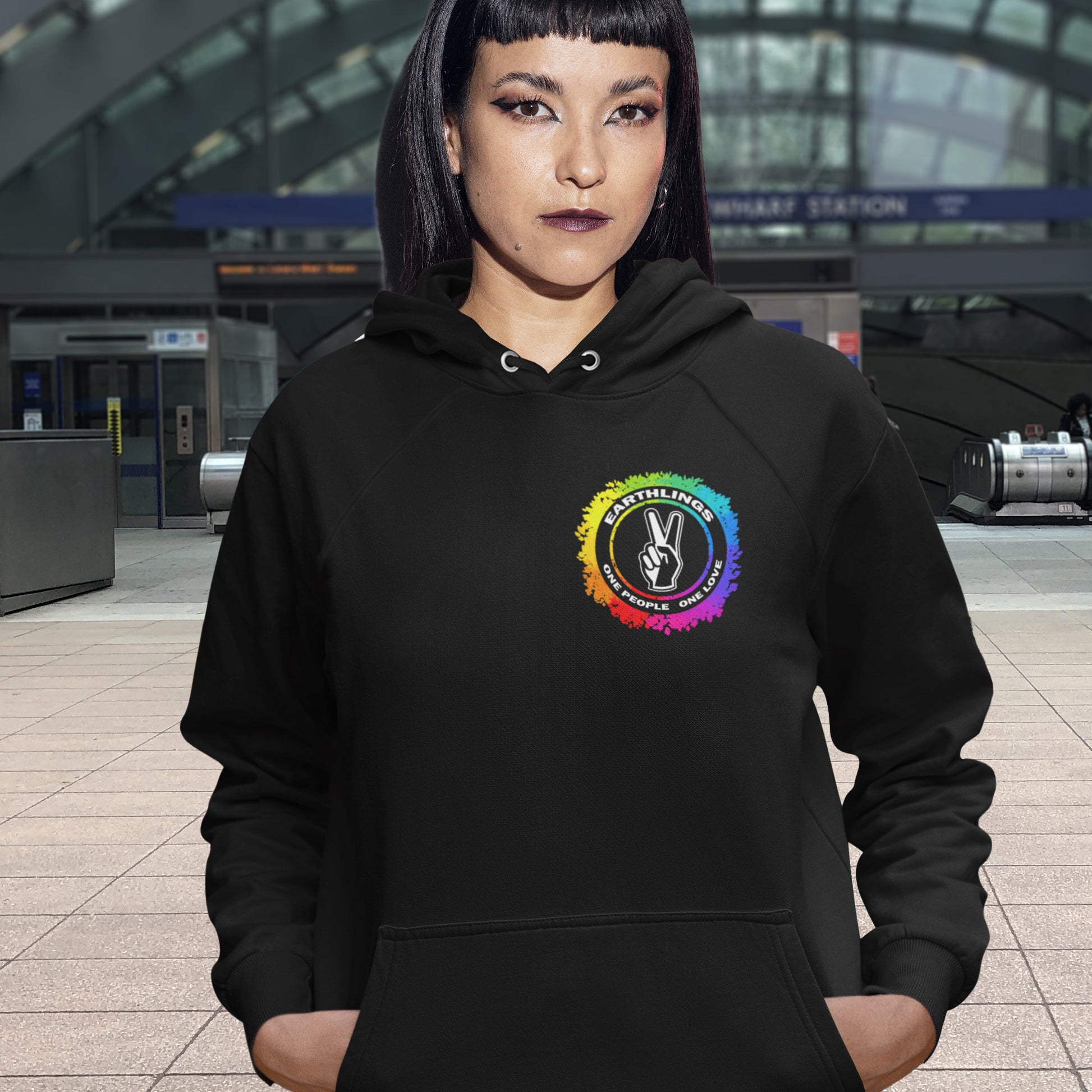 Person wearing a black hoodie with a colourful logo in an indoor setting. This ant-prejudice hoodie is LGTBQ+ friendly and anti-racism. We are all Earthlings and can live in peace and harmony if we put aside our prejudice and fear. This original design promotes social awareness and unity. Comfortable and practical. It's extra soft and has a convenient front pouch pocket. Made from organic cotton and recycled polyester, this anti prejudice hoodie is a great eco-friendly choice.