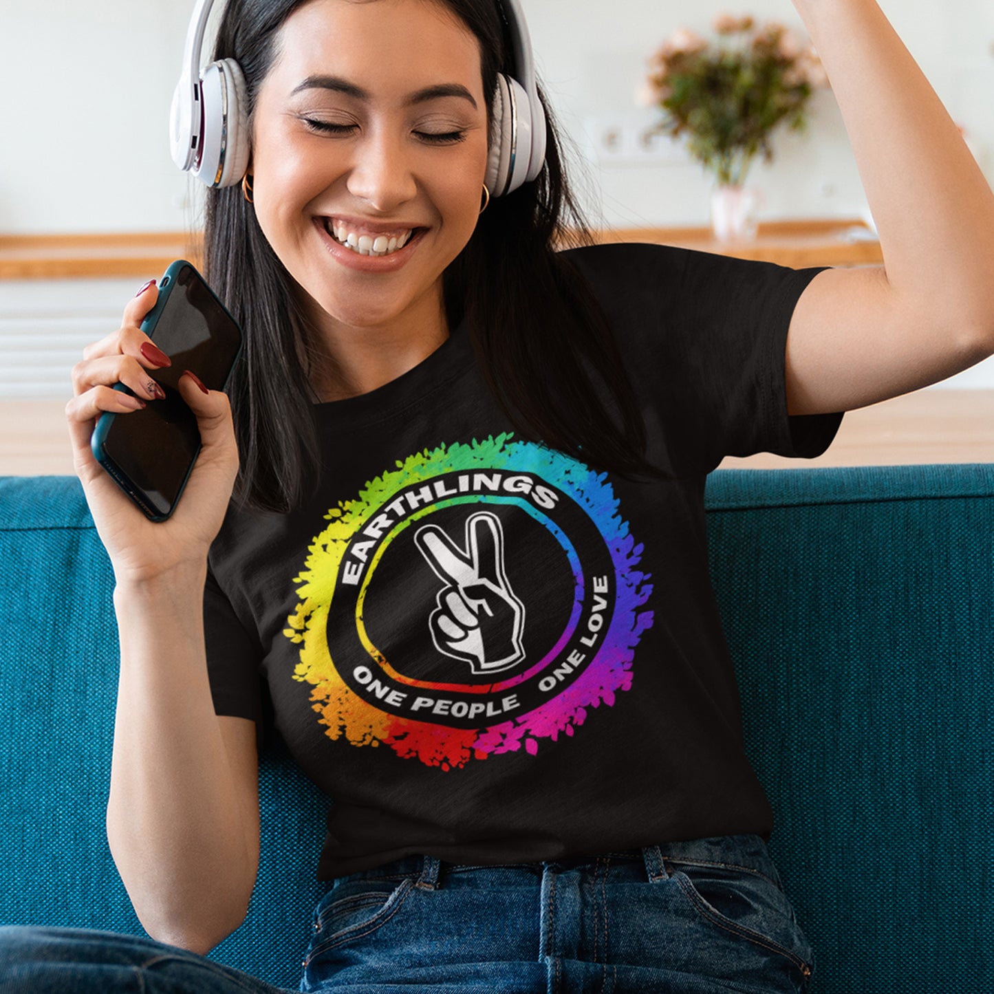 Woman wearing a black t-shirt with a rainbow design and text, sitting on a blue couch. This ant-prejudice t-shirt is LGTBQ+ friendly and anti-racism. We are all Earthlings and can live in peace and harmony if we put aside our prejudice and fear. This original design promotes social awareness and unity. Made from 100% organic ring-spun cotton, this anti prejudice t-shirt is unisex, high-quality, super comfy, and best of all, eco-friendly.