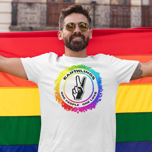 Man wearing a white t-shirt with an Earthling logo and text, standing behind a rainbow flag. This civil rights t shirt is LGTBQ+ friendly and anti-racism. We are all Earthlings and can live in peace and harmony if we put aside our prejudice and fear. This original design promotes social awareness and unity. Made from 100% organic ring-spun cotton, this gay t shirt design is unisex, high-quality, super comfy, and best of all, eco-friendly.