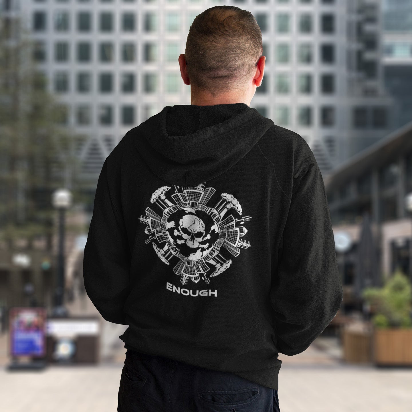Man in a city wearing a black hoodie with 'enough' text. An environmental hoodie highlighting an overcrowding concern. This original design is for all nature lovers who think that enough is enough and don't want to live in a concrete jungle. Comfortable and practical. It's extra soft and has a convenient front pouch pocket. Made from organic cotton and recycled polyester, this social awareness hoodie is a great eco-friendly choice.