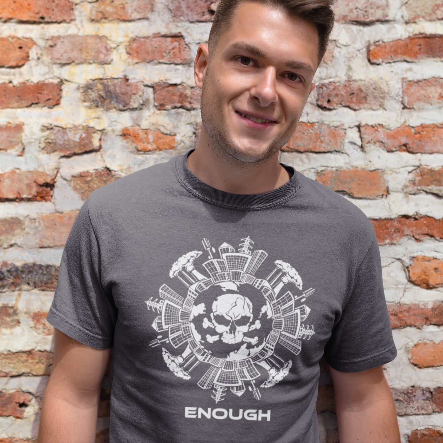 Man wearing an anthracite t-shirt with a white graphic design and 'ENOUGH' text against a brick wall. An environmental t-shirt highlighting an overcrowding concern. This original design is for all nature lovers who think that enough is enough and don't want to live in a concrete jungle. Made from 100% organic ring-spun cotton, this social political t-shirt is unisex, high-quality, super comfy, and best of all, eco-friendly.