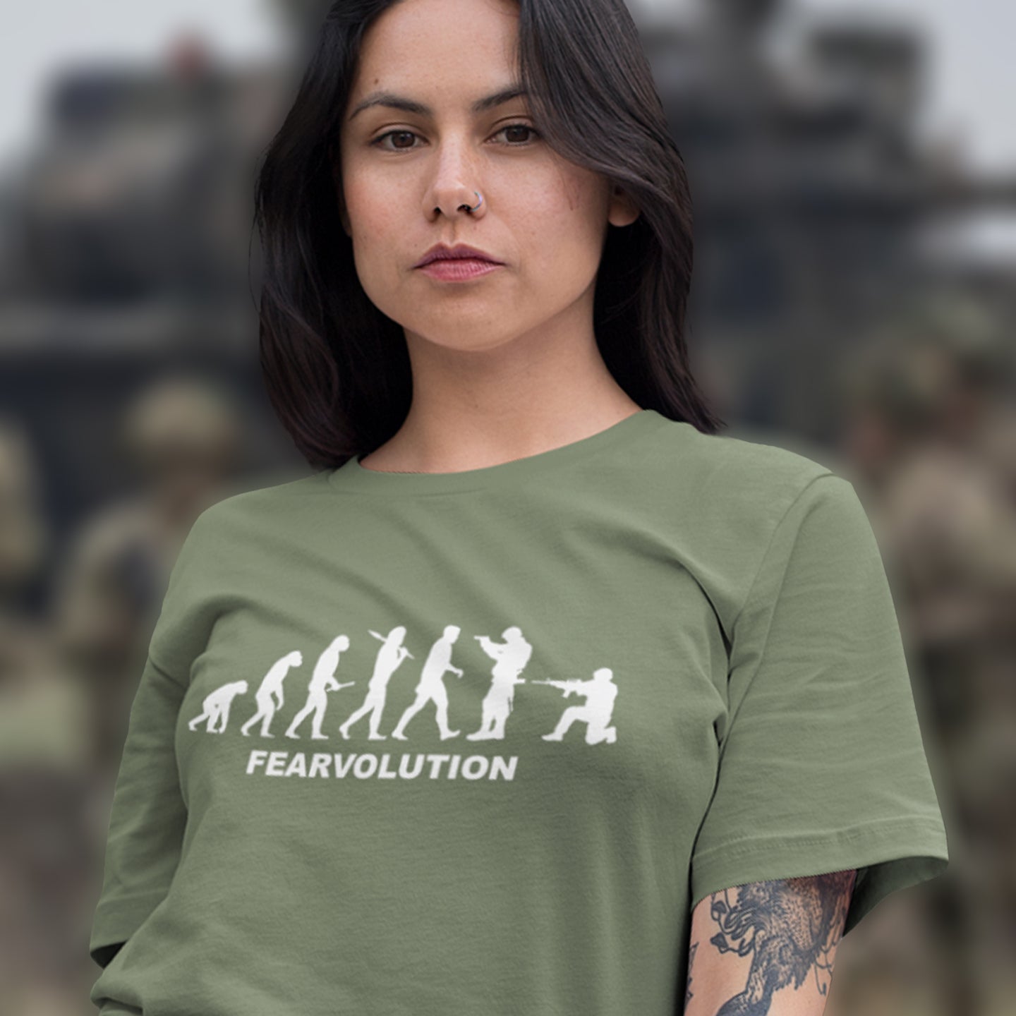 Woman wearing a khaki t-shirt with 'FEARVOLUTION' design in front of a blurred military-themed background. This satirical 'theory of evolution' t-shirt displays an alternative view of how we may evolve from here on. Fear is holding us back, fear of change. Made from 100% organic ring-spun cotton, this philosophy t-shirt is unisex, high-quality, super comfy, and best of all, eco-friendly.