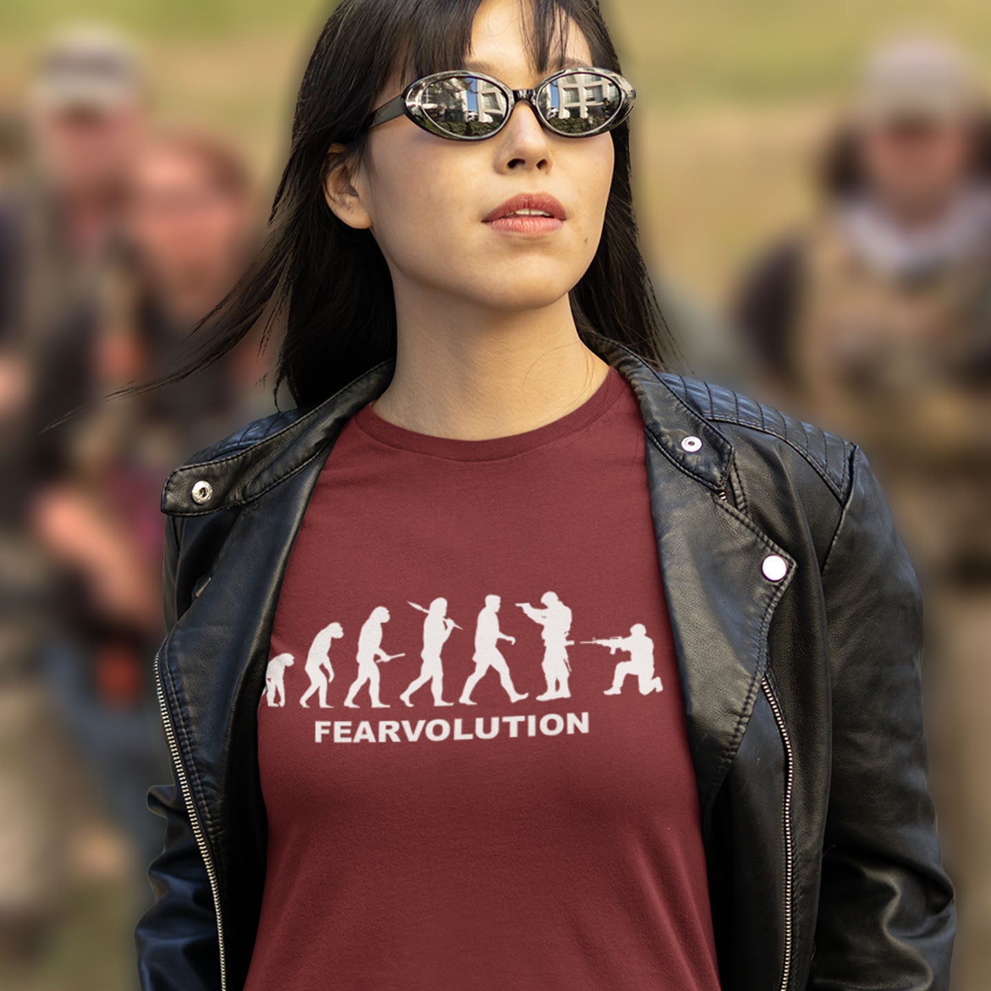 Person wearing a burgundy 'FEARVOLUTION' t-shirt with a black leather jacket and sunglasses, standing in a crowd. This social issues t-shirt displays an alternative view of how we may evolve from here on. Fear is holding us back, fear of change. Made from 100% organic ring-spun cotton, this emotional intelligence t-shirt is unisex, high-quality, super comfy, and best of all, eco-friendly.