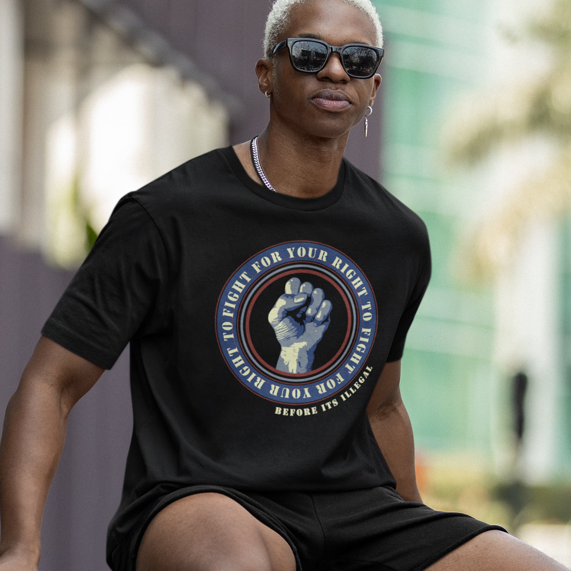 Person wearing a black t-shirt with a graphic design outdoors. A civil rights t-shirt reminding us not to take our freedom for granted. Fight for your right to demonstrate before it's made illegal. Made from 100% organic ring-spun cotton, this anti-establishment t-shirt is unisex, high-quality, super comfy, and best of all, eco-friendly.