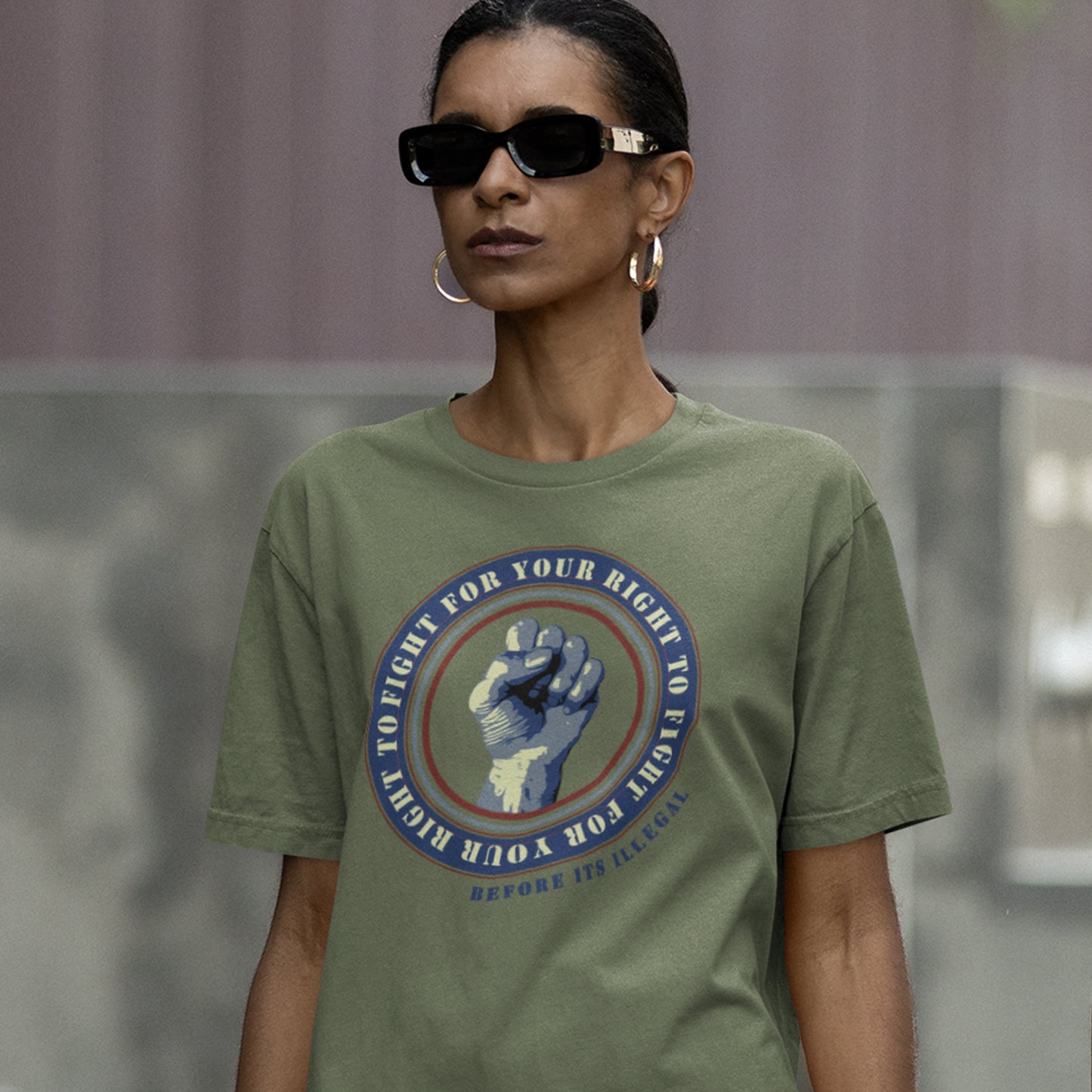 Person wearing a khaki t-shirt with a graphic design and sunglasses. A civil rights t-shirt reminding us not to take our freedom for granted. Fight for your right to demonstrate before it's made illegal. Made from 100% organic ring-spun cotton, this anti-establishment t-shirt is unisex, high-quality, super comfy, and best of all, eco-friendly.
