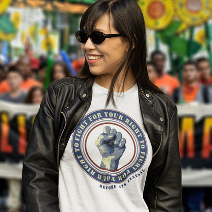 Woman wearing a white t-shirt with a graphic design and black leather jacket in front of a blurred crowd. A civil rights t-shirt reminding us not to take our freedom for granted. Fight for your right to demonstrate before it's made illegal. Made from 100% organic ring-spun cotton, this anti-establishment t-shirt is unisex, high-quality, super comfy, and best of all, eco-friendly.