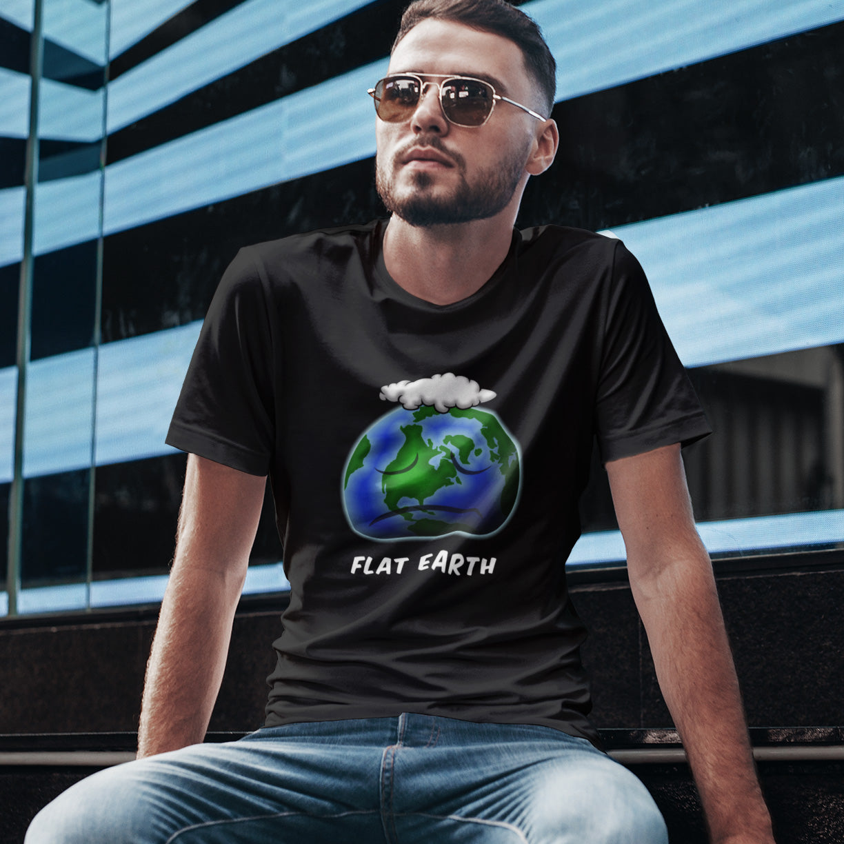 Man wearing a black t-shirt with a 'Flat Earth' graphic design, sitting in front of a modern building. This funny conspiracy theorist t shirt plays on the idea of the earth being flat. Could it just be a little bored or depressed. Made from 100% organic ring-spun cotton, this funny flat earth conspiracy theory t shirt is unisex, high-quality, super comfy, and best of all, eco-friendly.