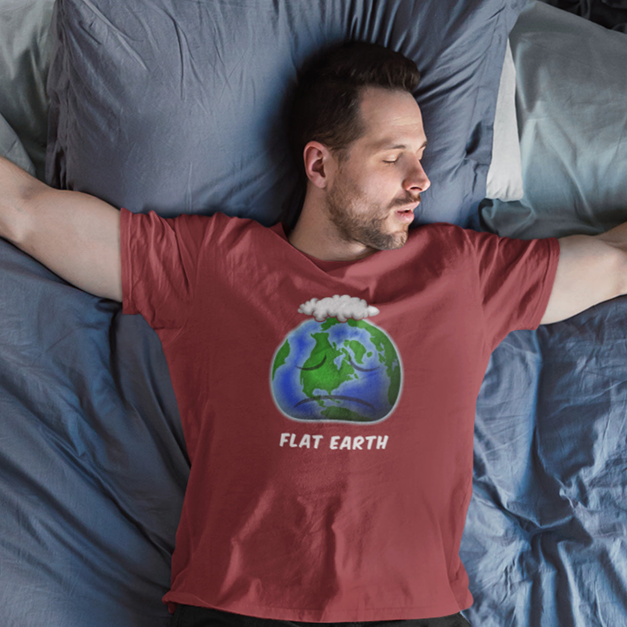 Man wearing a burgundy 'Flat Earth' t-shirt lying in bed with blue bedding. This funny conspiracy theorist t shirt plays on the idea of the earth being flat. Could it just be a little bored or depressed. Made from 100% organic ring-spun cotton, this funny flat earth conspiracy theory t shirt is unisex, high-quality, super comfy, and best of all, eco-friendly.