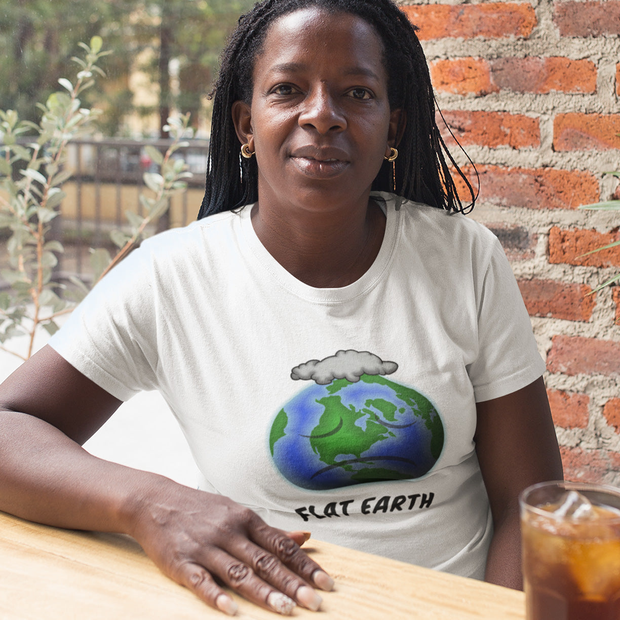Person wearing a white t-shirt with a 'Flat Earth' graphic sitting at a table. This funny conspiracy theorist t shirt plays on the idea of the earth being flat. Could it just be a little bored or depressed. Made from 100% organic ring-spun cotton, this funny flat earth conspiracy theory t shirt is unisex, high-quality, super comfy, and best of all, eco-friendly.