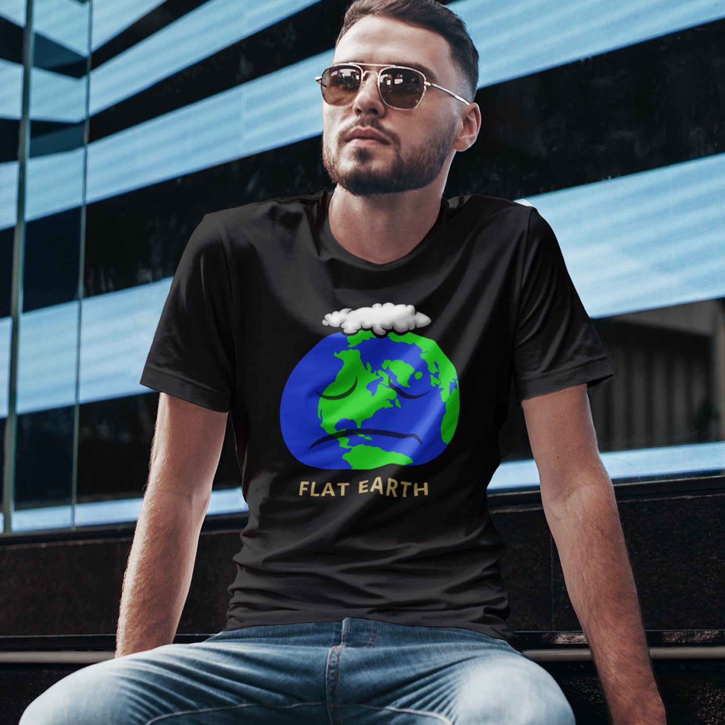 Man wearing a black t-shirt with a 'Flat Earth' graphic design sitting in front of a modern building. This funny conspiracy theory t-shirt plays on the idea of the earth being flat. Could it just be a little bored or depressed. Made from 100% organic ring-spun cotton, this funny flat earth theory t-shirt is unisex, high-quality, super comfy, and best of all, eco-friendly.