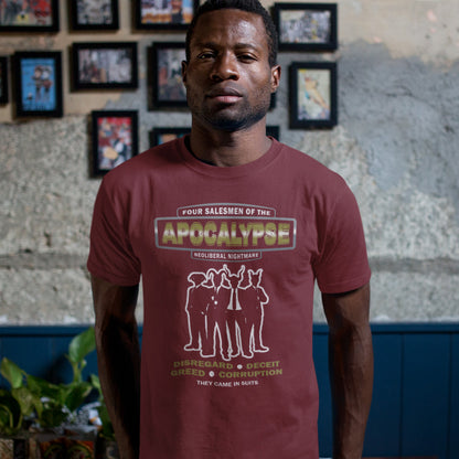 Man wearing a red t-shirt with graphic design and text, standing in front of a wall with framed pictures. An anti capitalism t shirt with a biblical undertone. A satirical design looking at how neoliberalism and it's hidden inequalities could bring on the downfall of civilised society and the form it will take. Made from 100% organic ring-spun cotton, this non conformist t shirt is a total must-have. It's high-quality, super comfy, and best of all, eco-friendly.