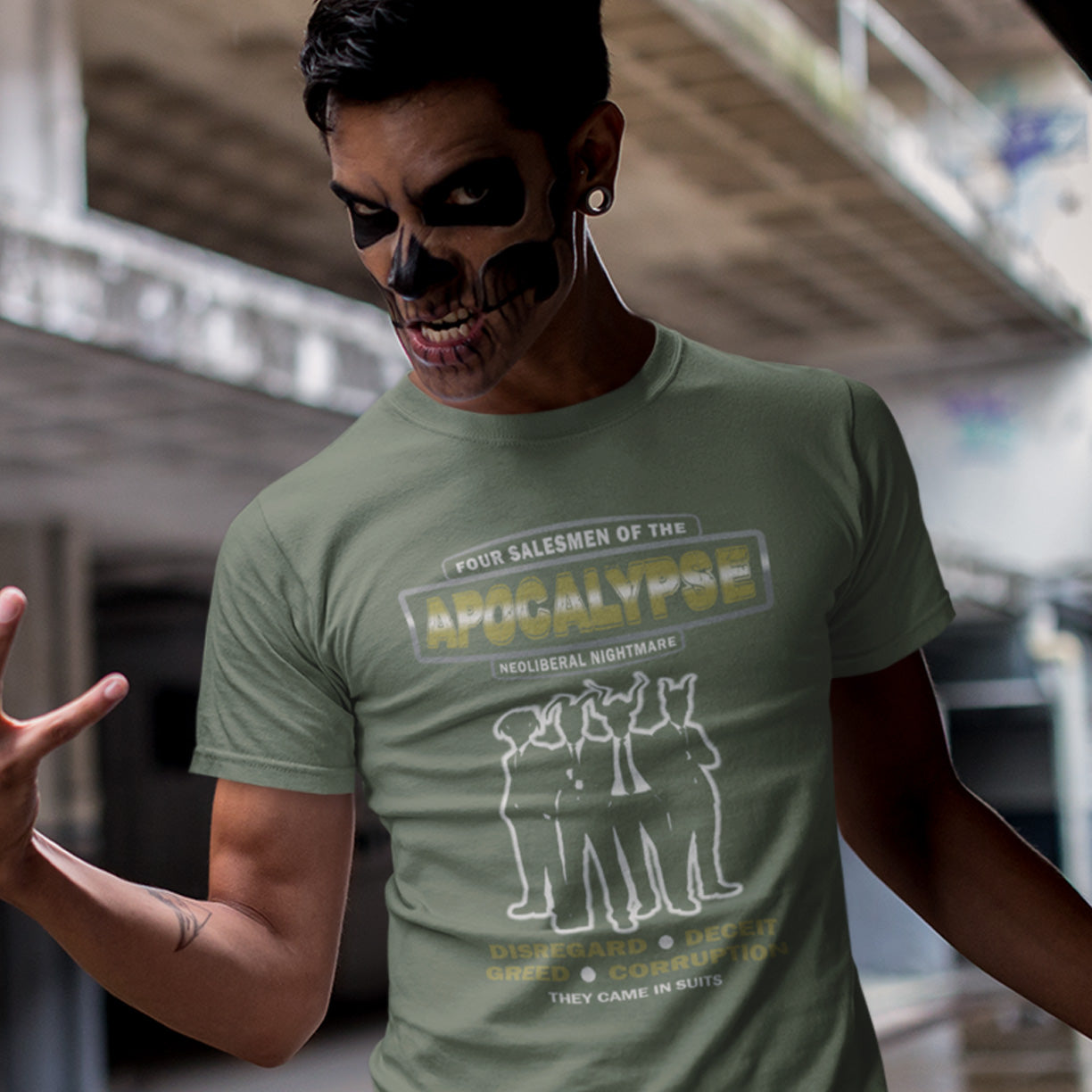 Person wearing a green t-shirt with graphic design and text, standing in an indoor setting. A political t-shirt with a biblical undertone. A satirical design looking at how neoliberalism could bring on the downfall of civilised society and the form it will take. Made from 100% organic ring-spun cotton, this unisex political t-shirt is a total must-have. It's high-quality, super comfy, and best of all—eco-friendly.