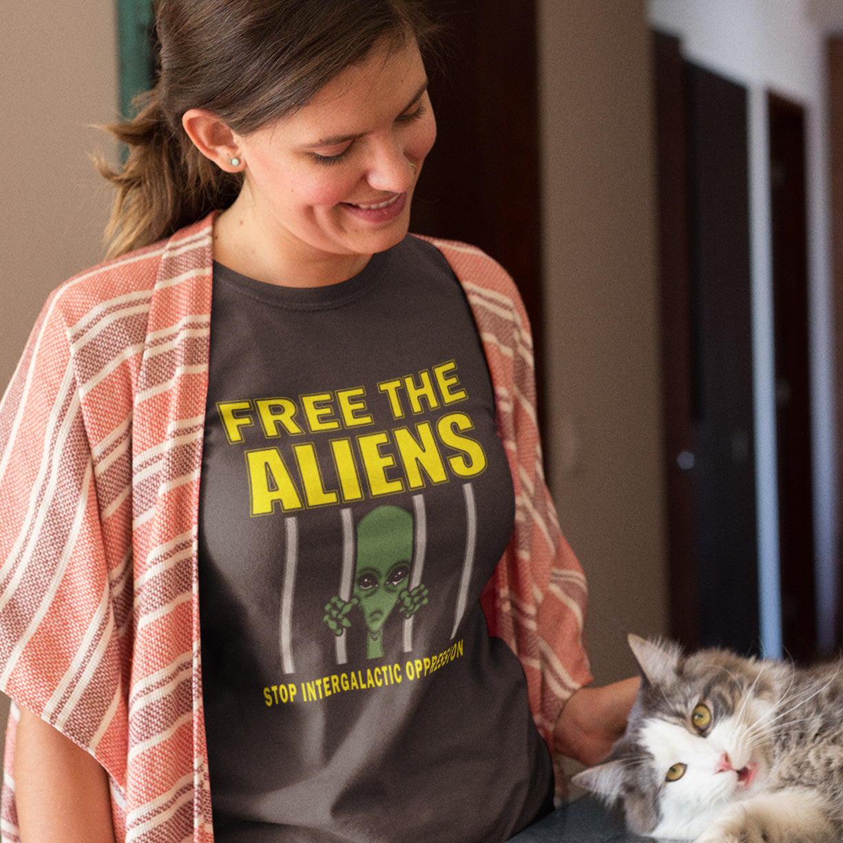 Person wearing a 'Free the Aliens' shirt sitting with a cat. This funny alien conspiracy theory t-shirt alludes to there being more than just UFO crashes that we are not being told about. With all these alien sightings they must detaining them somewhere ! Made from 100% organic ring-spun cotton, this conspiracy theory t-shirt is unisex, high-quality, super comfy, and best of all, eco-friendly.