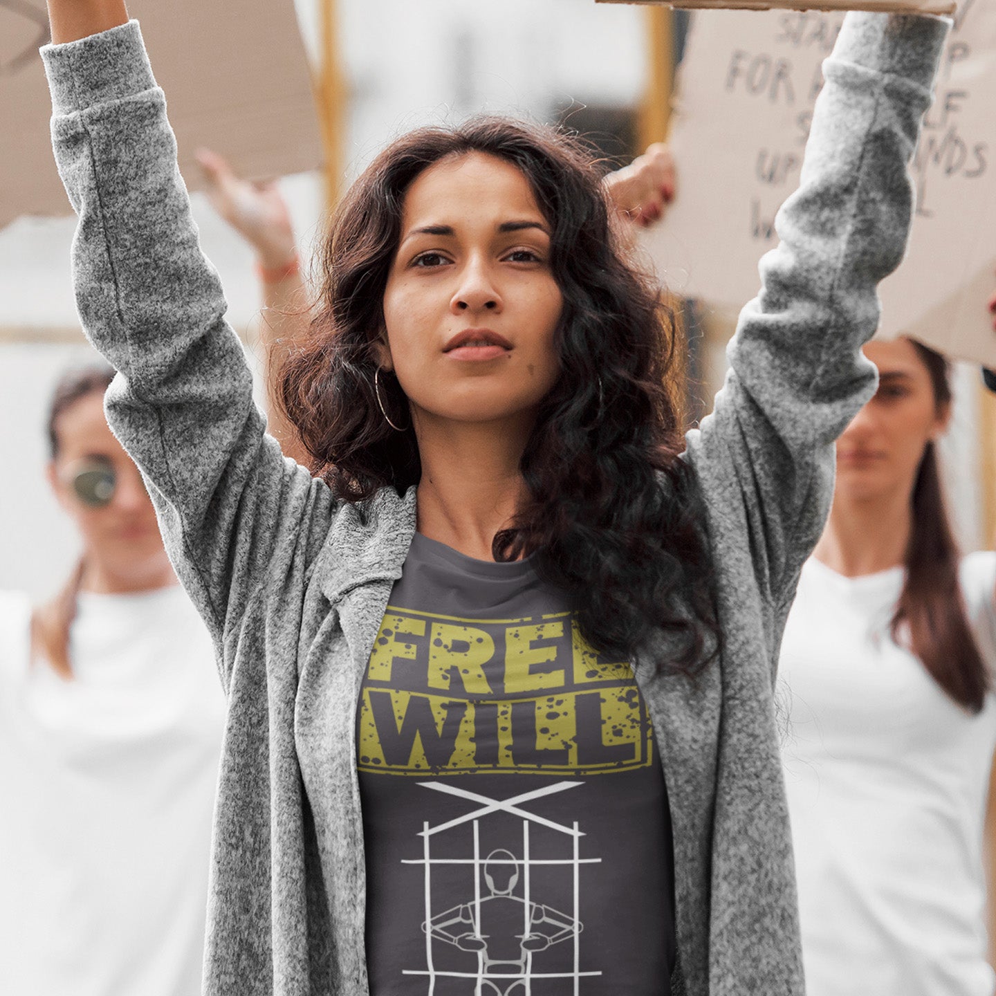 Woman with raised arms in a protest or rally setting, wearing a 'Free Will' t-shirt. A civil liberties t shirt design to promote independent thought and self awareness. If you are feeling overwhelmed by influence, join the 'free will' movement. Made from 100% organic ring-spun cotton, this social awareness t-shirt is unisex, high-quality, super comfy, and best of all, eco-friendly.